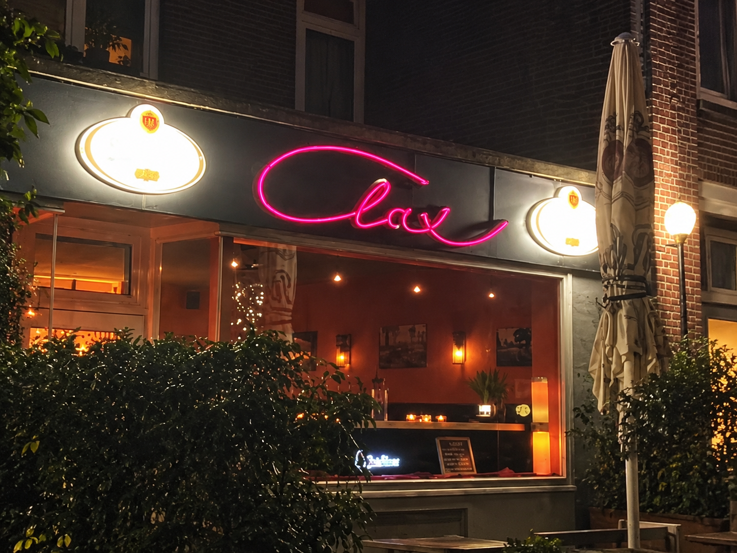 Clax-Fassade bei Nacht mit rosa Neon-Schriftzug und warmem Fensterlicht