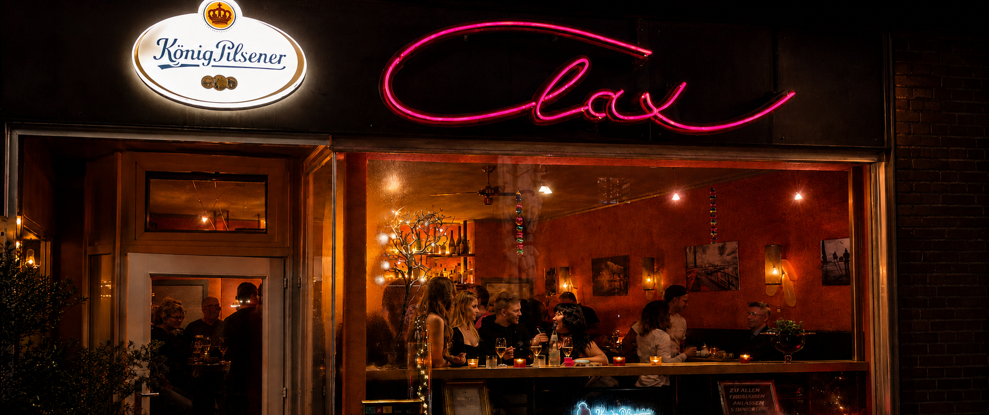 Clax-Fassade am Abend mit rosa Neon-Schriftzug und Gästen im Fenster